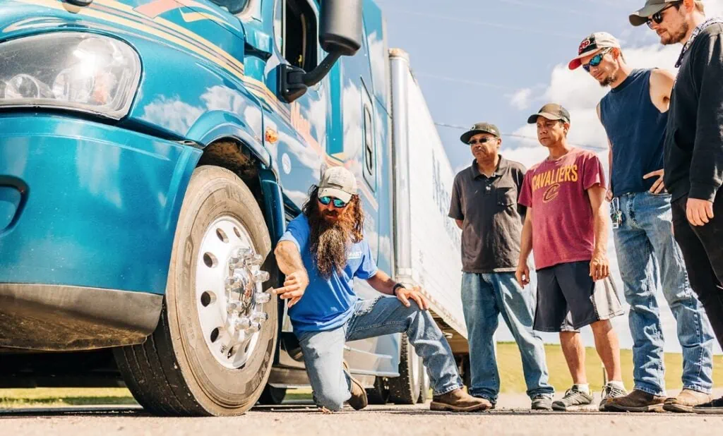 A group of truck drivers standing in front of a semi truck.